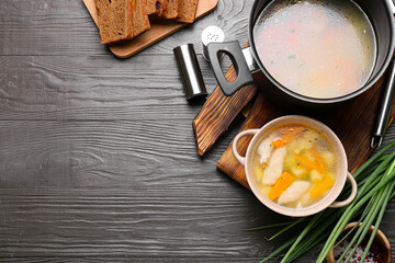 Composition with bowl of tasty dumpling soup and ingredients on dark wooden background, closeup