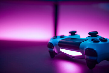 Low angle view game controller on table. Blank dual display and pink wall in background.