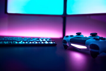 Low angle view game controller on table. Dual display and pink illuminated wall in background.