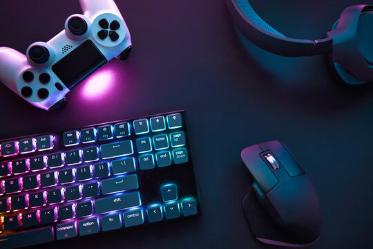 Top Down View Of Various Gaming Accessories Laying On Table. Colorful Illuminated Devices.