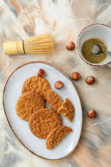 Plate with tasty hojicha cookies, chasen and powder on grunge background