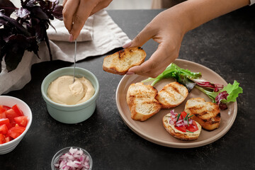 Woman cooking delicious vegetarian bruschettas at table in kitchen