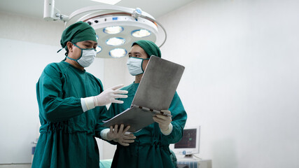 Doctors or surgeons with Physician assistant standing to discussion about a patient case in an operating room before performing difficult operations, Surgery on patient that requires knowledge.