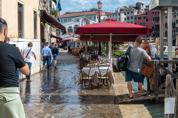 Riva del vin flooded at high tide, with the rialto bridge in the background.