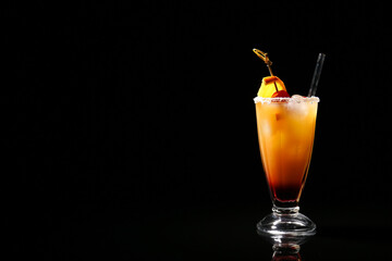 Glass of tasty Tequila Sunrise cocktail on dark background
