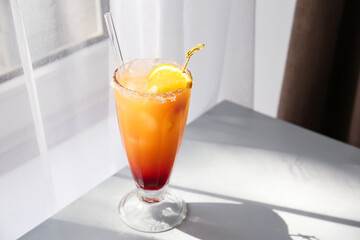 Glass of tasty Tequila Sunrise cocktail on table