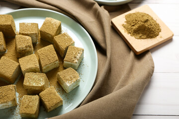 Plate with tasty hojicha marshmallows on light wooden background, closeup