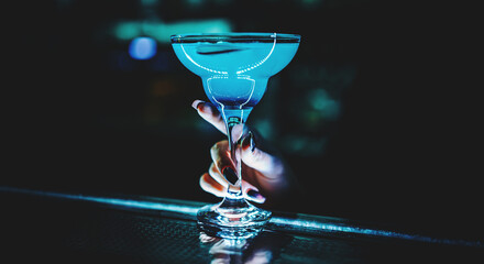 close-up of woman bartender hand holds cold blue cocktail Blue Lagoon in bar