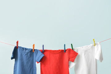 T-shirts hanging on rope against blue background