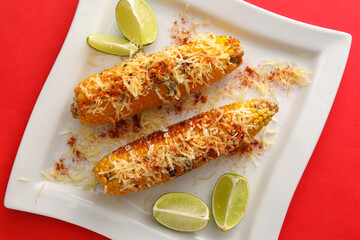 Plate with delicious Elote Mexican Street Corn on red background