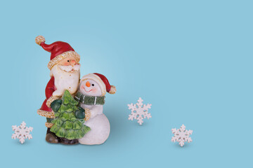 Creative Christmas idea with Santa Claus and Snowman in an embrace on a bright blue background.