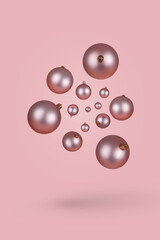 Minimal Christmas composition. Pink Christmas ornaments flying on bright pink background.