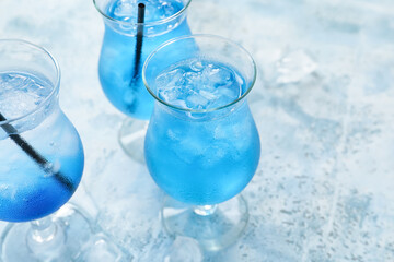 Glasses of Blue Lagoon cocktail on color background, closeup