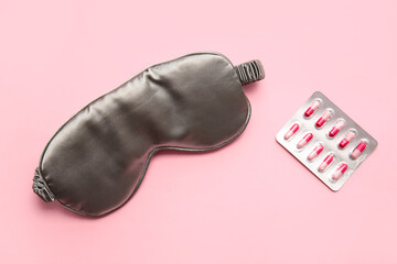 Stylish sleep mask and pills on color background