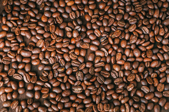 Roasted coffee grains on a dark wooden table. Coffee background.