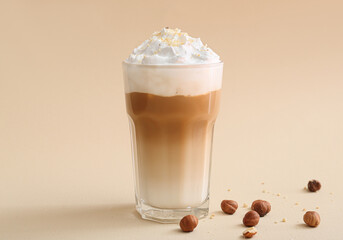 Glass of tasty latte with nuts on beige background
