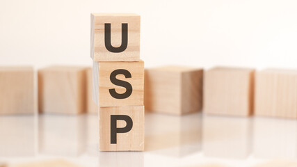 wooden cubes with letters USP arranged in a vertical pyramid, on the light background, reflection surface, concept