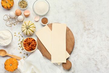 Raw dough and ingredients for preparing pumpkin strudel on light background