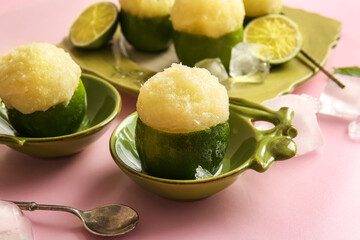 Plate and bowls with tasty ice creams in lime peels on color background