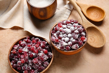 Bowls with tasty sugared cranberries on beige background