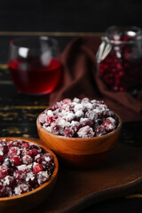 Bowls with tasty sugared cranberries on black wooden background