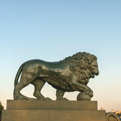 Fototapeta na wymiar stone sculpture of a lion putting his paw on a ball on the embankment of the Neva River in St. Petersburg, Russia. The concept of strength, power.