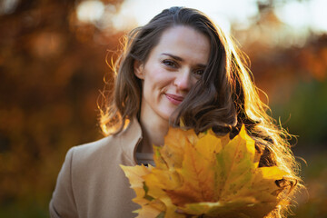 smiling trendy woman in brown coat and yellow hat