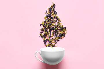 Creative composition with cup and dried butterfly pea flower tea on color background