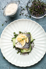 Plate of tasty sea bass fish on grey background
