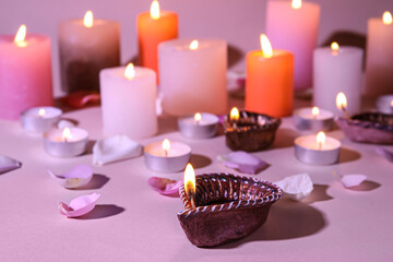 Obraz na płótnie Canvas Diya lamps for Diwali, candles and flower petals on color background