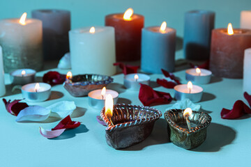 Diya lamps for Diwali, candles and flower petals on color background
