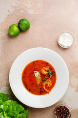 tom yum in white plate on concrete background. Spicy Thai food with ingredients on table. Spicy Thai food top view