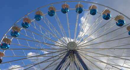 Riesenrad vor strahlend blauem Himmel mit weißen Wölkchen