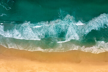 Obraz na płótnie Canvas Crashing turquoise ocean waves on yellow sandy beach