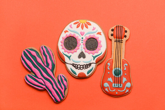 Cookies in shape of skull, guitar and cactus on red background. El Dia de Muertos