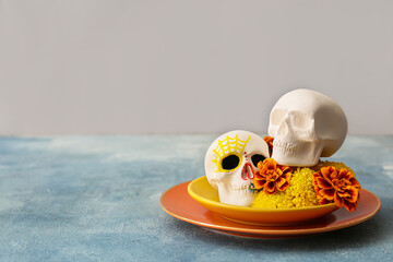 Plates with human skulls for Mexico's Day of the Dead (El Dia de Muertos) and flowers on light background