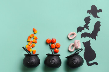 Witch's cauldrons with candies and Halloween decor on blue background