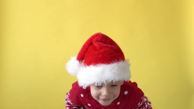 Portrait Emotion Cute Happy Cheerful Chubby Preschool Baby Boy in Santa Hat Looking On Camera At Yellow Background. Child Playing Christmas Scene Celebrating Birthday. Kid Have Fun Spend New Year Time