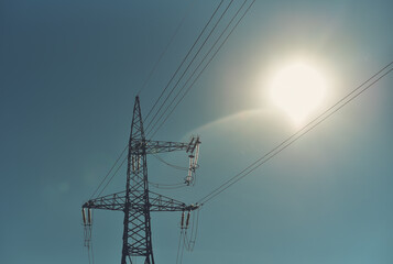 High voltage power line with sun in the form of a on light bulb. Work electric power concept
