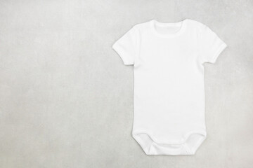 White baby girl or boy bodysuit mockup flat lay on the gray concrete background. Design onesie...