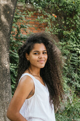Portrait of a cuban teenage girl in a garden with walls full of green plants, closeup latin cuban teenage woman
