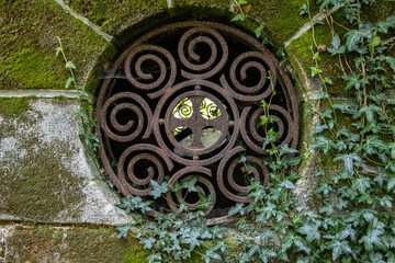 A Round window with bars in a historic stone tomb.