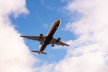 White blue Russian 2-engine Passenger Turbojet aircraft with chassis takes off against the blue sky close up bottom view, recreation, tourism