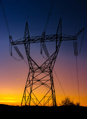 Silhouette of a high voltage tower with the sunset on a background