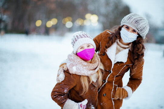 happy elegant mom and child outdoors in city park in winter