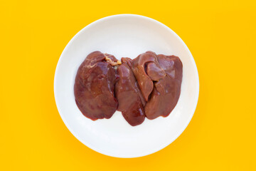 Chicken livers in white plate on yellow background.