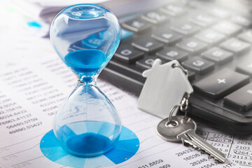 Real  estate concept - hourglass, key and calculator. Best time for investment.