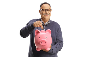 Mature man putting a coin into a piggy bank and smiling at camera