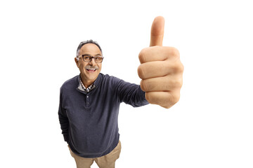 Cheerful mature casual male smiling and gesturing a thumb up sign in front of camera
