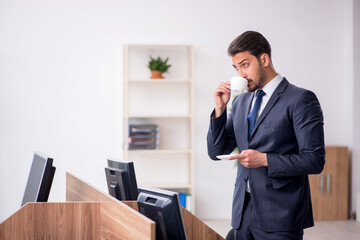 Young male employee drinking coffee during break